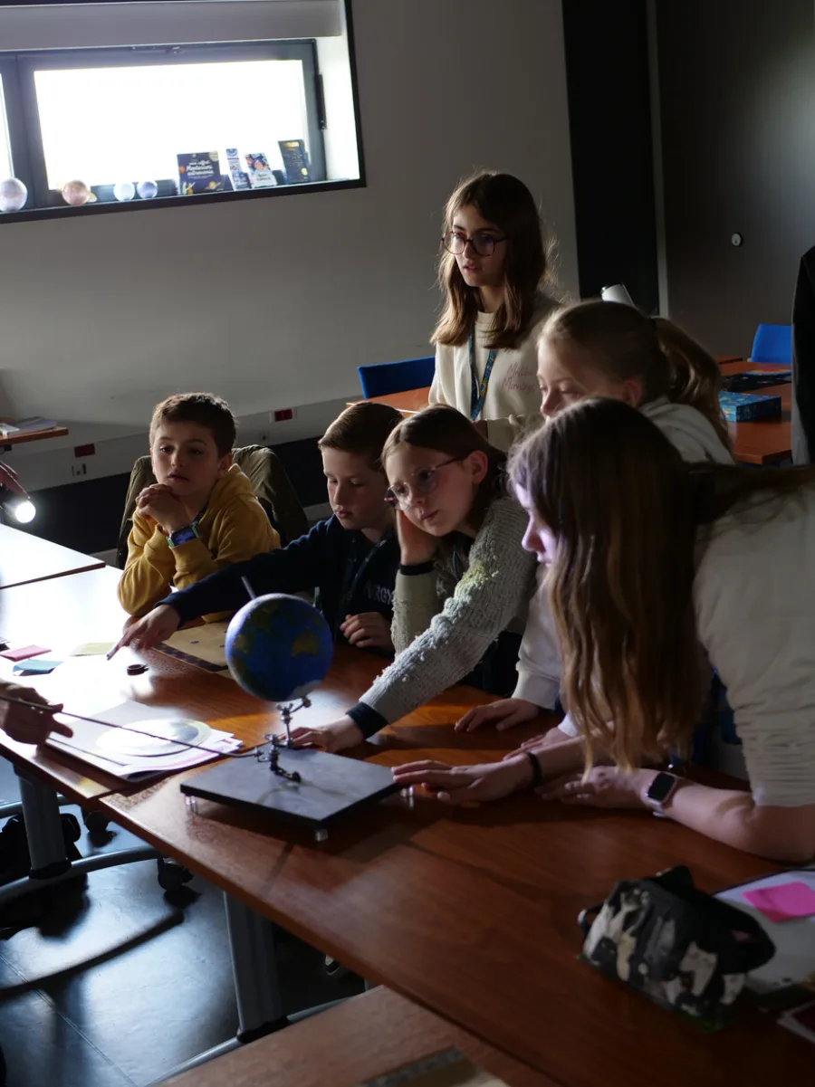 Des élèves autour d'un globe lors d'un atelier à La Coupole